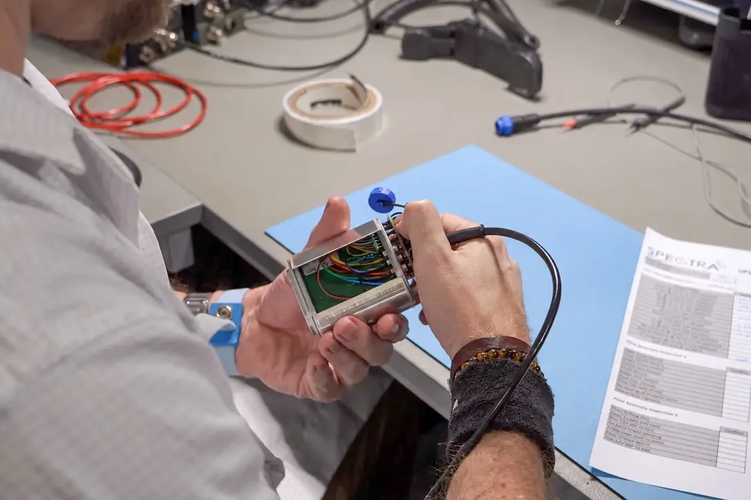 Spectra Group engineer testing an electronic assembly at a workbench.